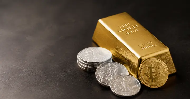 Gold bar, silver coins, and a Bitcoin token on a dark tabletop